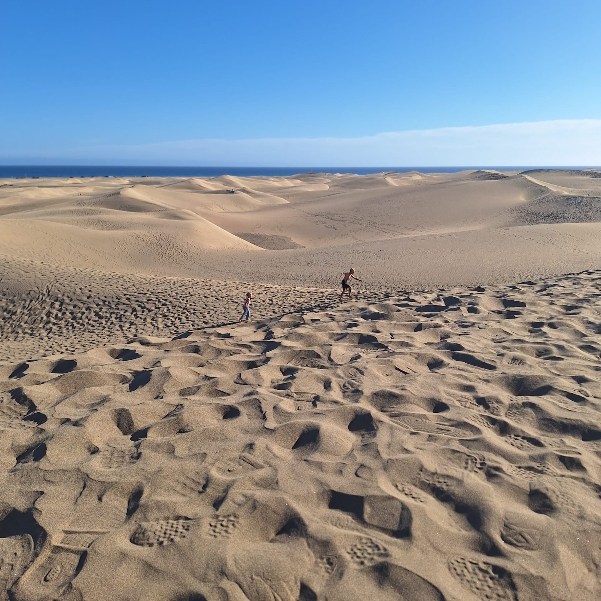 Children running across the vast Maspalomas sand dunes