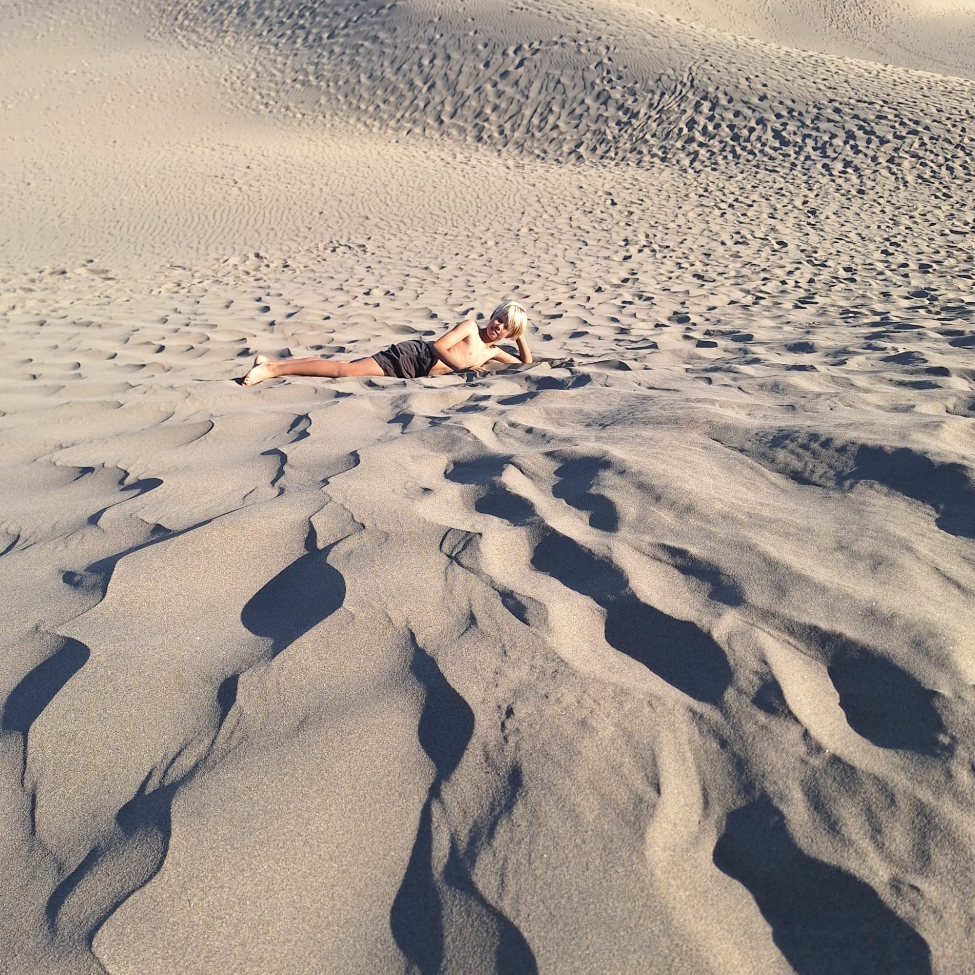 Child relaxing in the rippled sand of the Maspalomas dunes