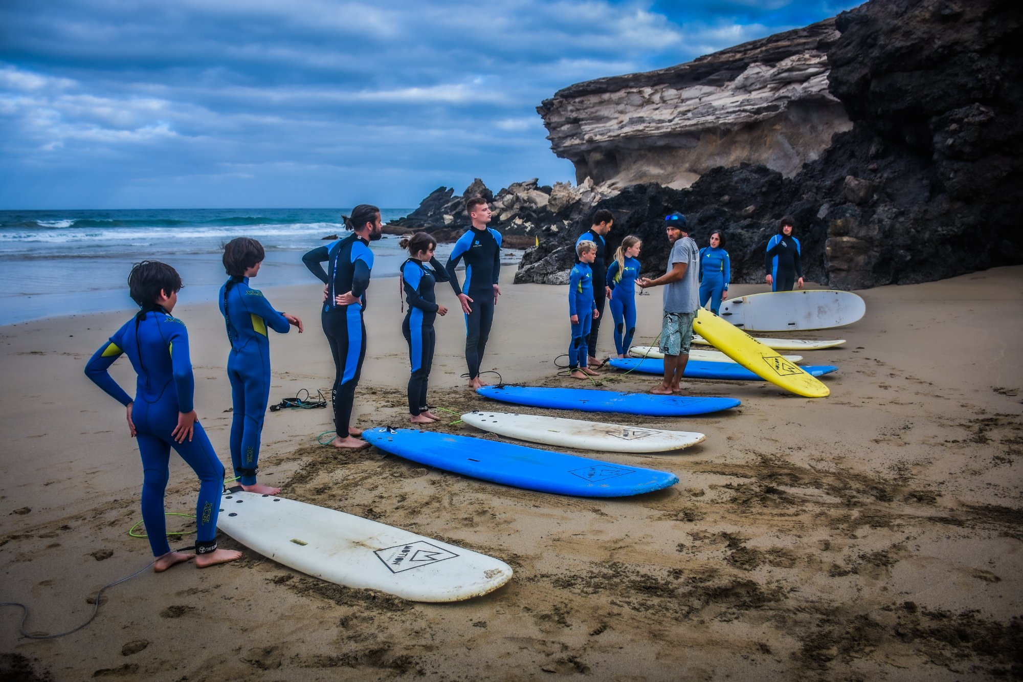 Group surf lesson on the beach with teens and families learning together