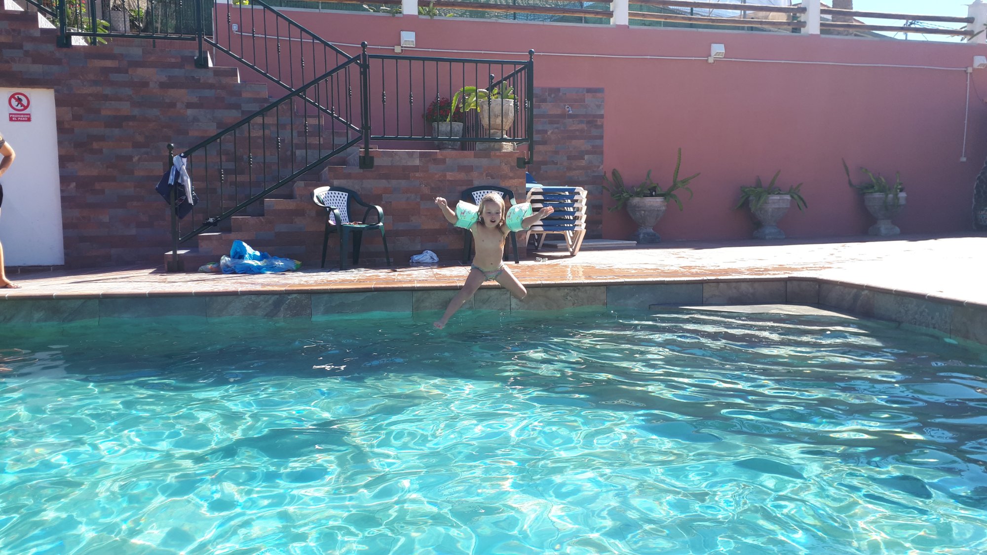 Child jumping into a swimming pool in the sunshine in Gran Canaria