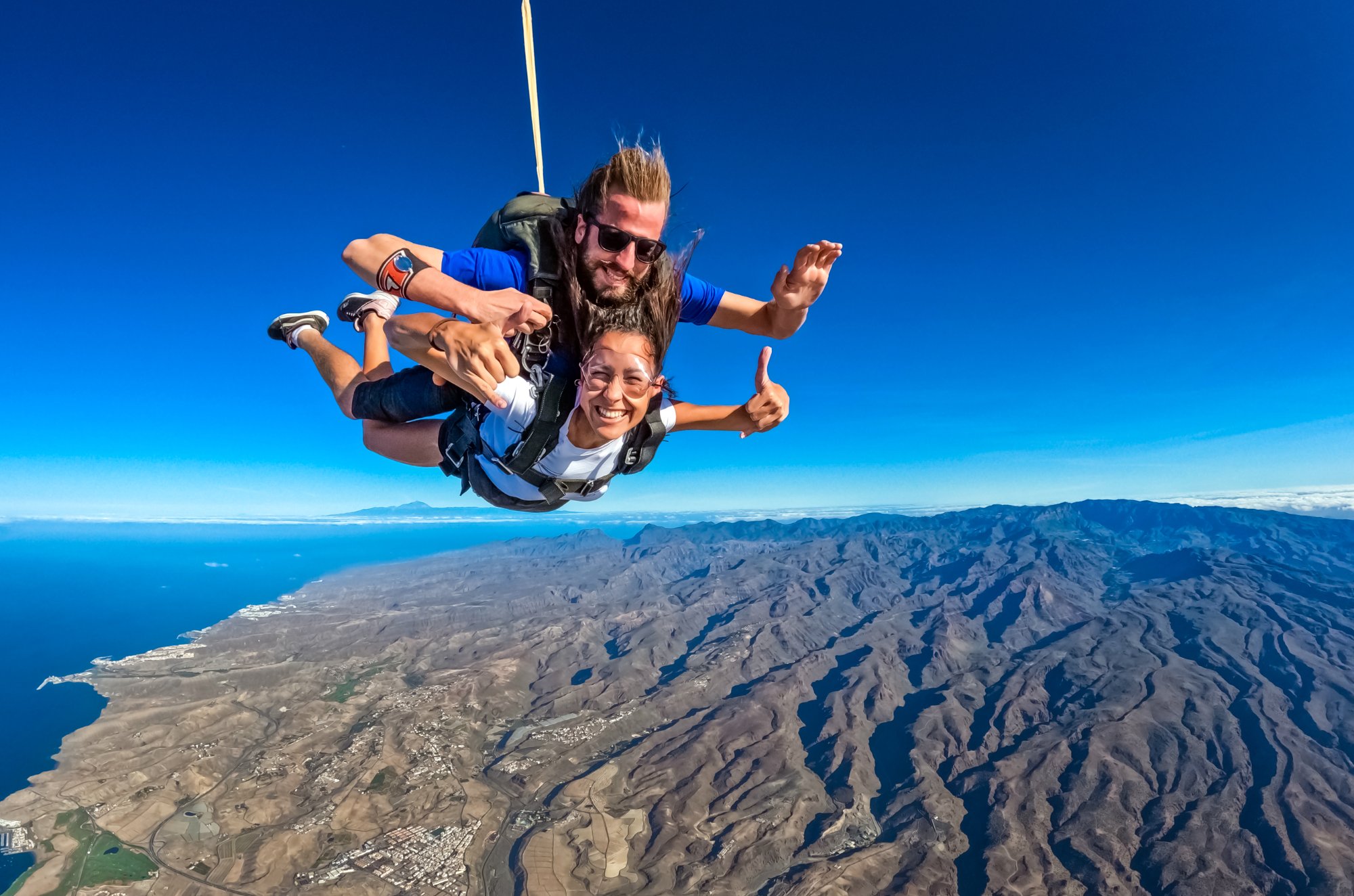 Tandem skydivers in freefall above Gran Canaria