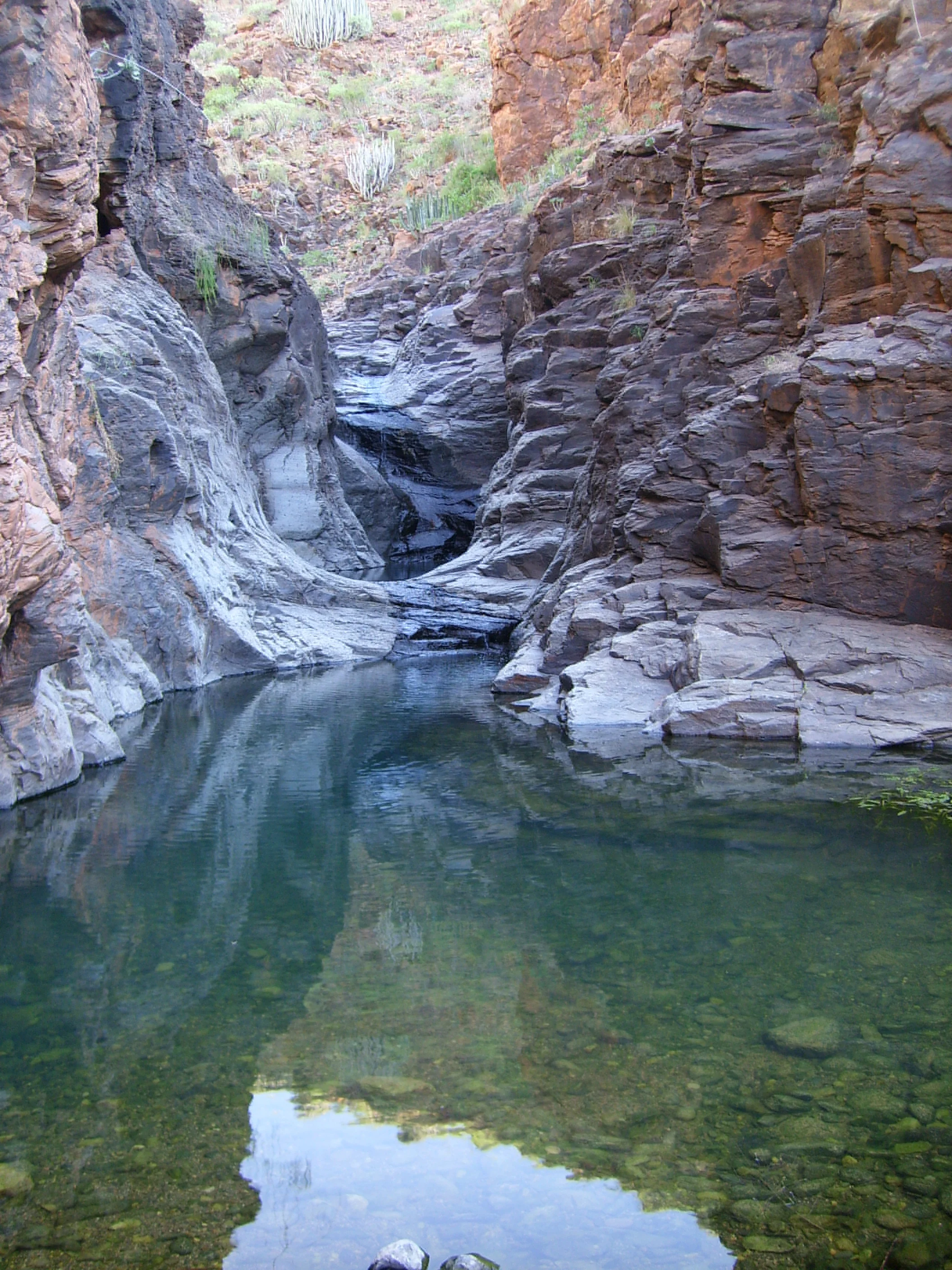 Crystal clear natural rock pool hidden in a dramatic volcanic gorge in Gran Canaria